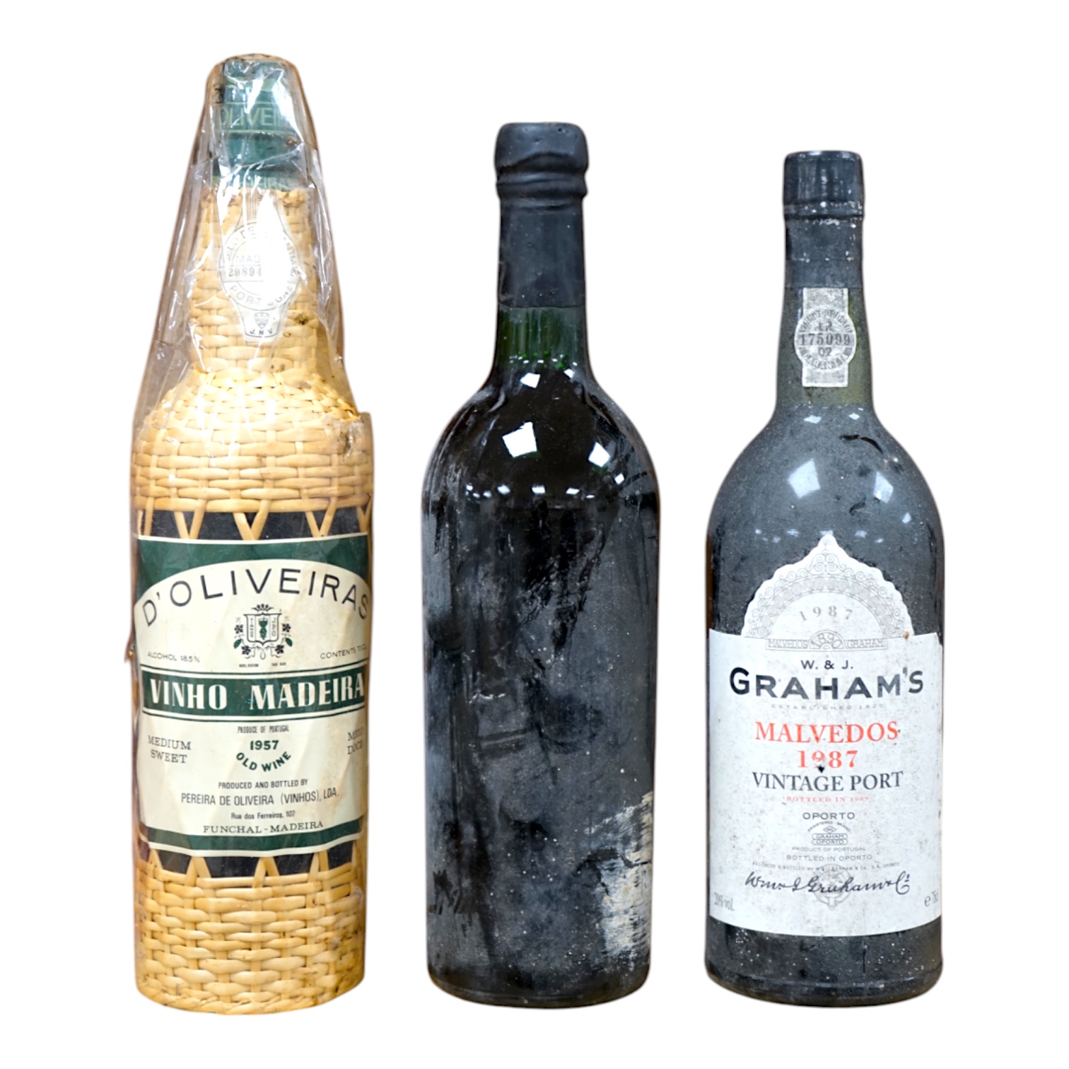 One bottle of Grahams 1963 port, label lacking, one bottle of Graham‘s Malvedos vintage port 1987 and one bottle of D’Oliveiras Vinho Madeira 1957 old wine (3) Condition - fair, storage history unknown